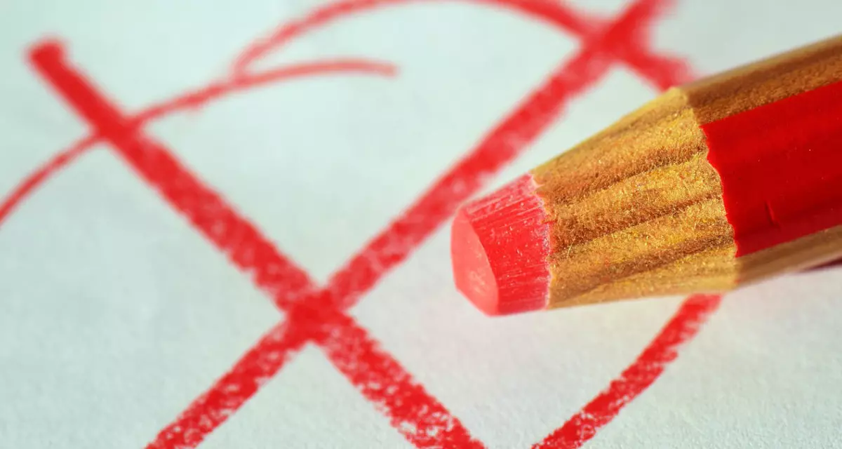 Ein roter Stift malt ein Kreuz in einen Kreis.